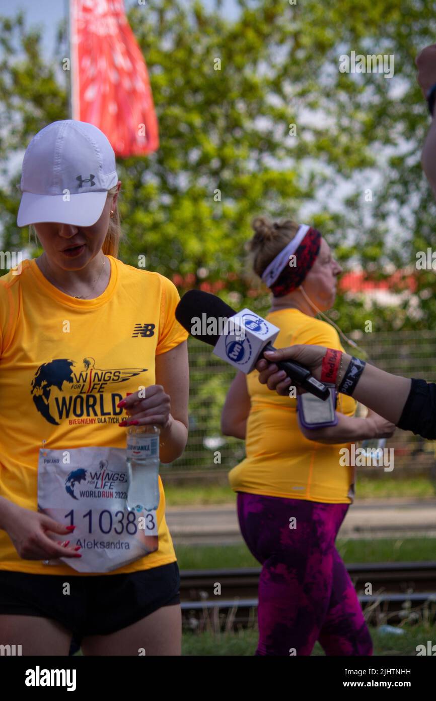 Ein Reporter mit Mikrofon interviewt einen Läufer beim Wings for Life World Run Stockfoto