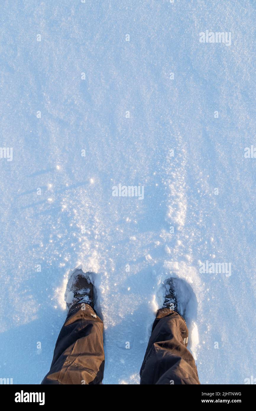 Niedriger Abschnitt einer Person, die an einem sonnigen Tag im Winter im Schnee steht, von oben betrachtet. Speicherplatz kopieren. Stockfoto