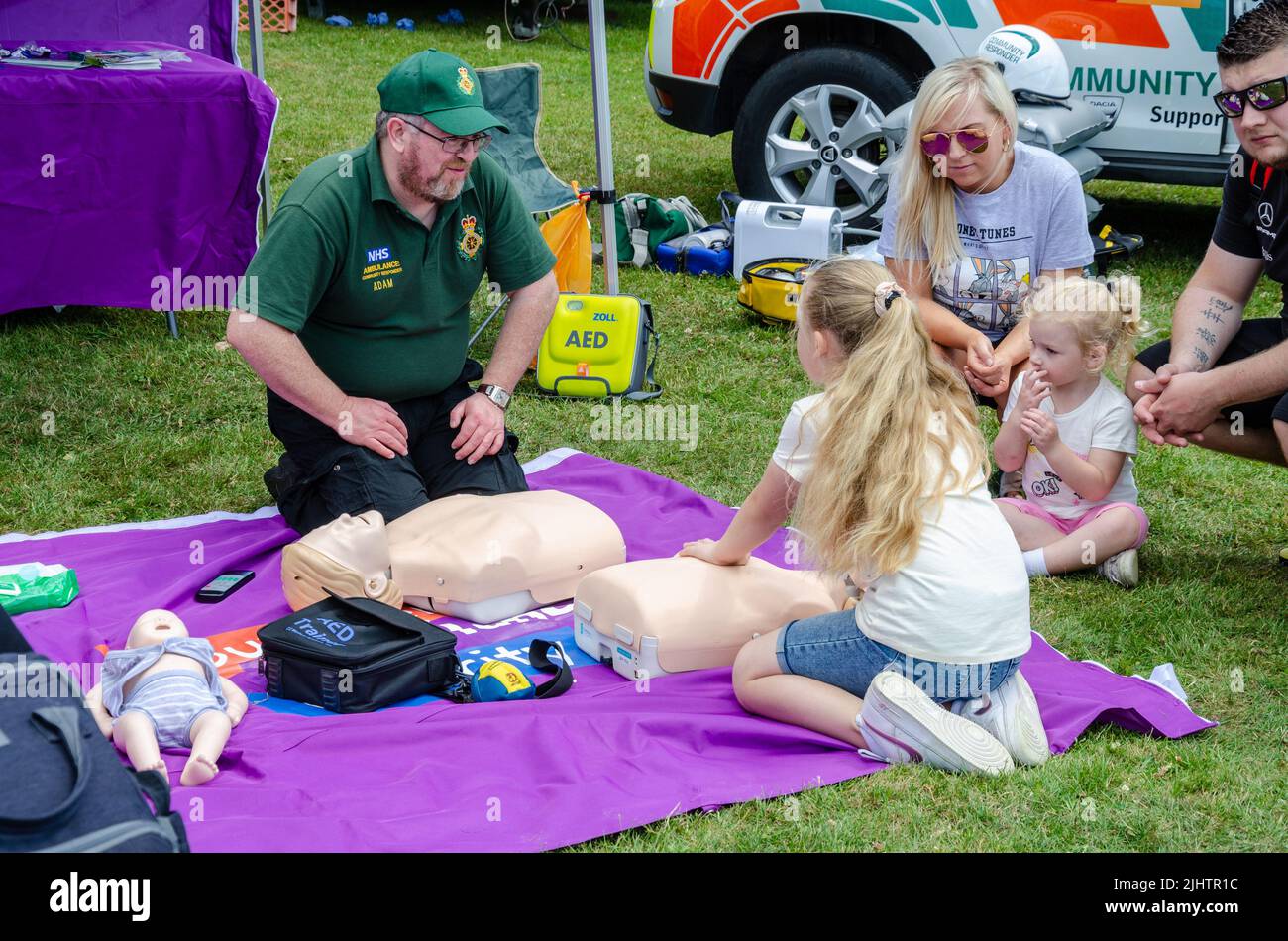 Ein Sanitäter, der einem Mädchen auf der „The Bukshire Motor Show“ in Reading, Großbritannien, die HLW an einer Schaufensterpuppe beibringt Stockfoto