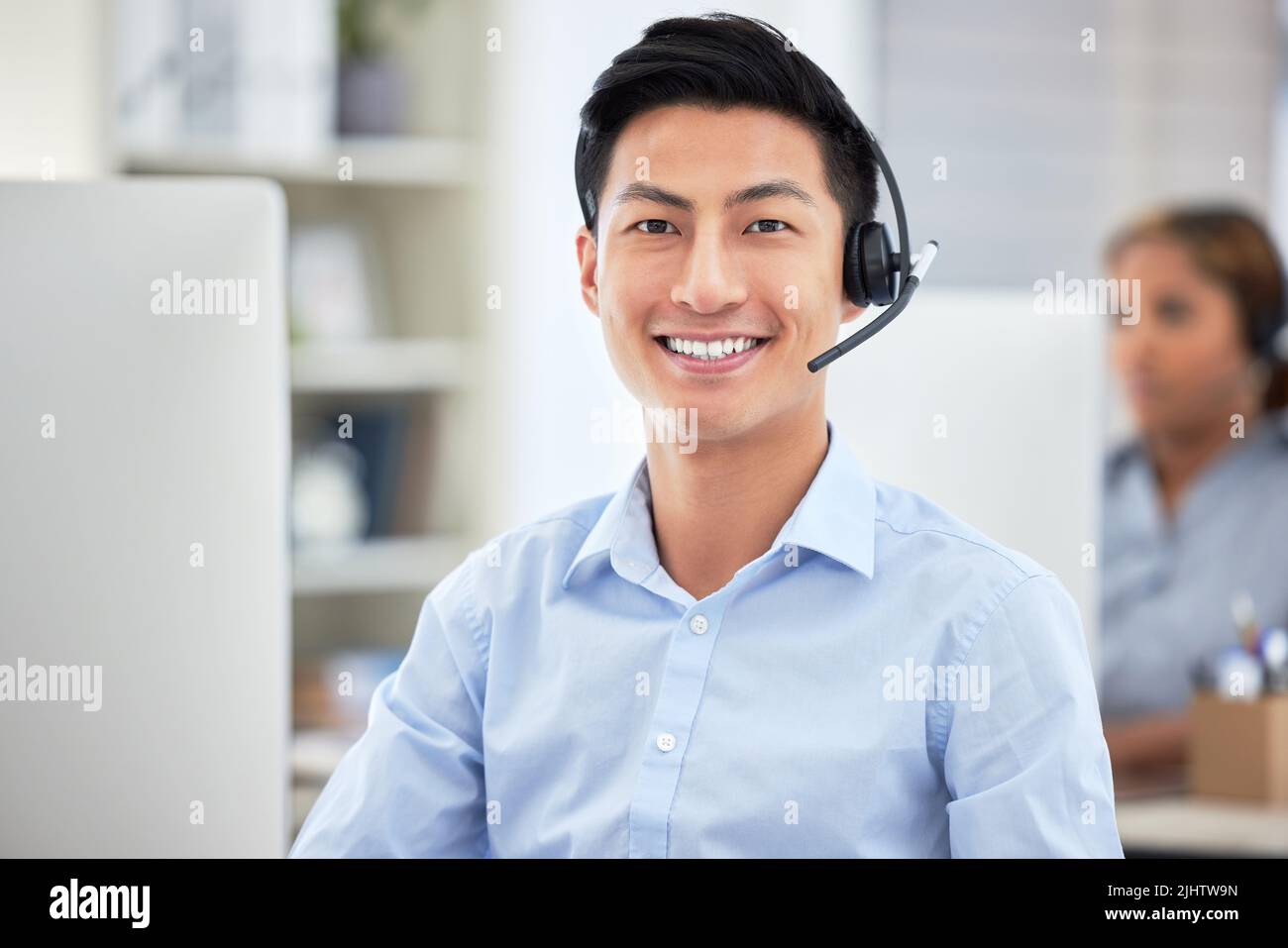 Porträt eines asiatischen Callcenter-Agenten, der während der Arbeit am Computer im Büro mit einem Headset spricht. Selbstbewusste und lächelnde Geschäftsmann Beratung und Betrieb Stockfoto