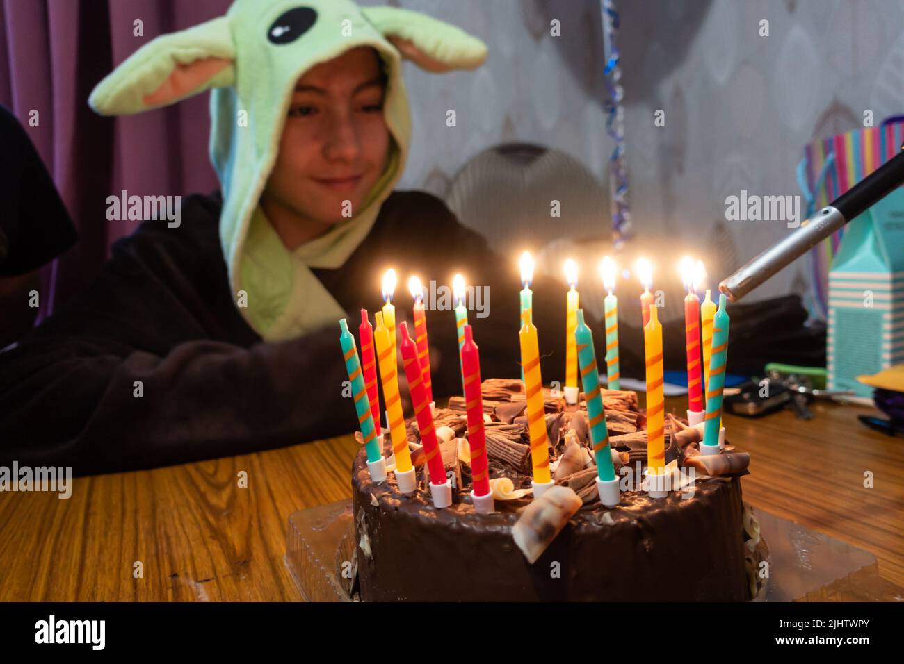 Kerzen auf einem Schokoladengeburtstag, der mit einem Gasfeuerzeug angezündet wird, während der Geburtstagsjunge zuschaut. Stockfoto