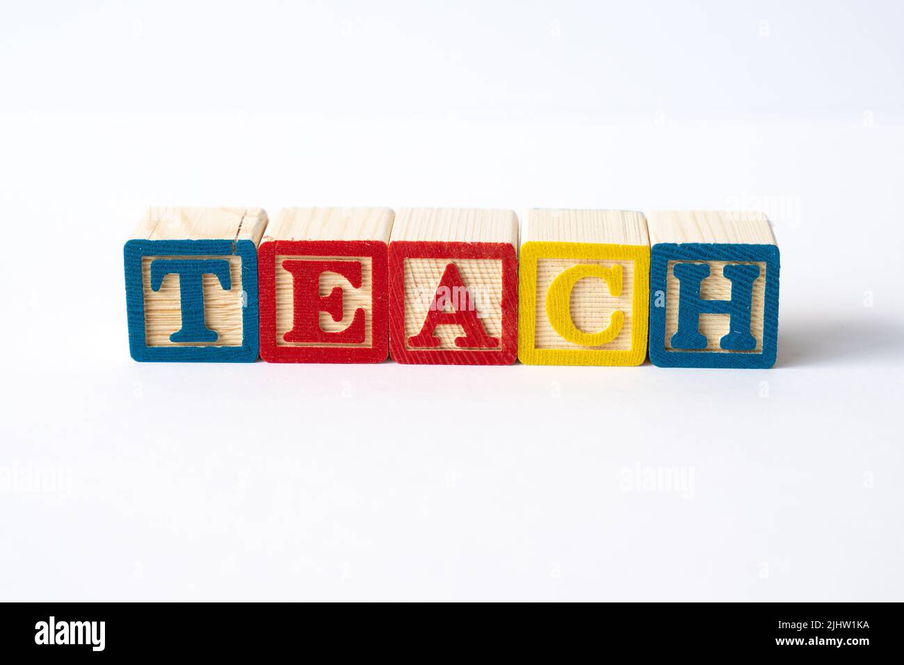 Das Wort Teach mit bunten Spielzeugblöcken auf weißem Hintergrund Stockfoto