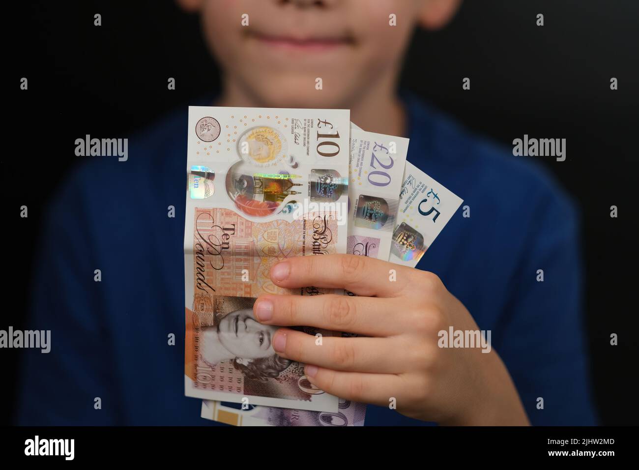 Pfund Sterling Banknoten von 10, 20, 5 Pfund in den Händen eines glücklichen Kindes gesehen. Konzept für persönliche Finanzen und Kinder. Stockfoto