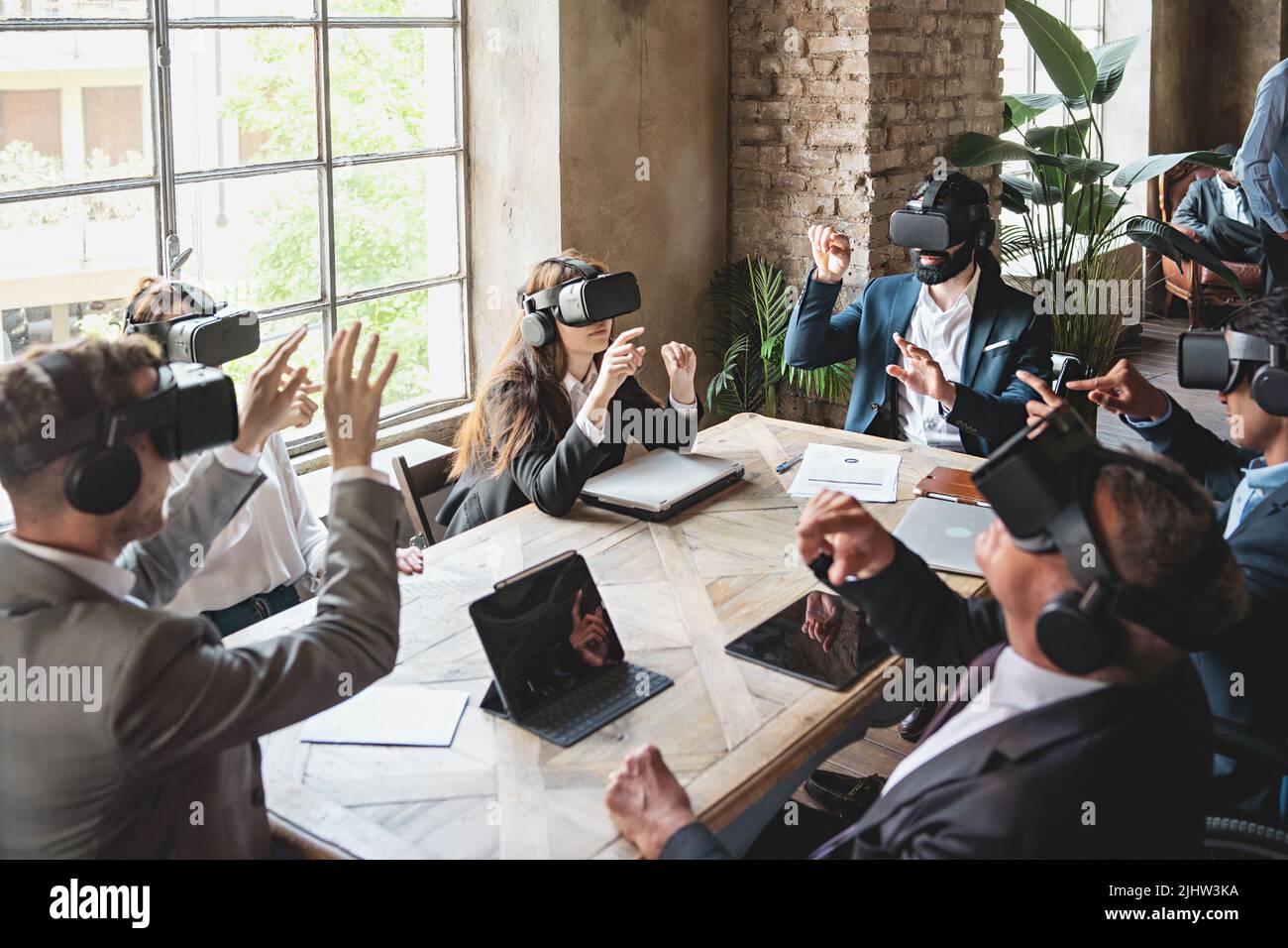 Eine Gruppe von Geschäftsleuten, die ein virtuelles Projekt mit einer 360 3D-VR-Brille erkunden und am Tisch sitzen - die Menschen treffen sich in einer Metaverse-Realität - busin Stockfoto