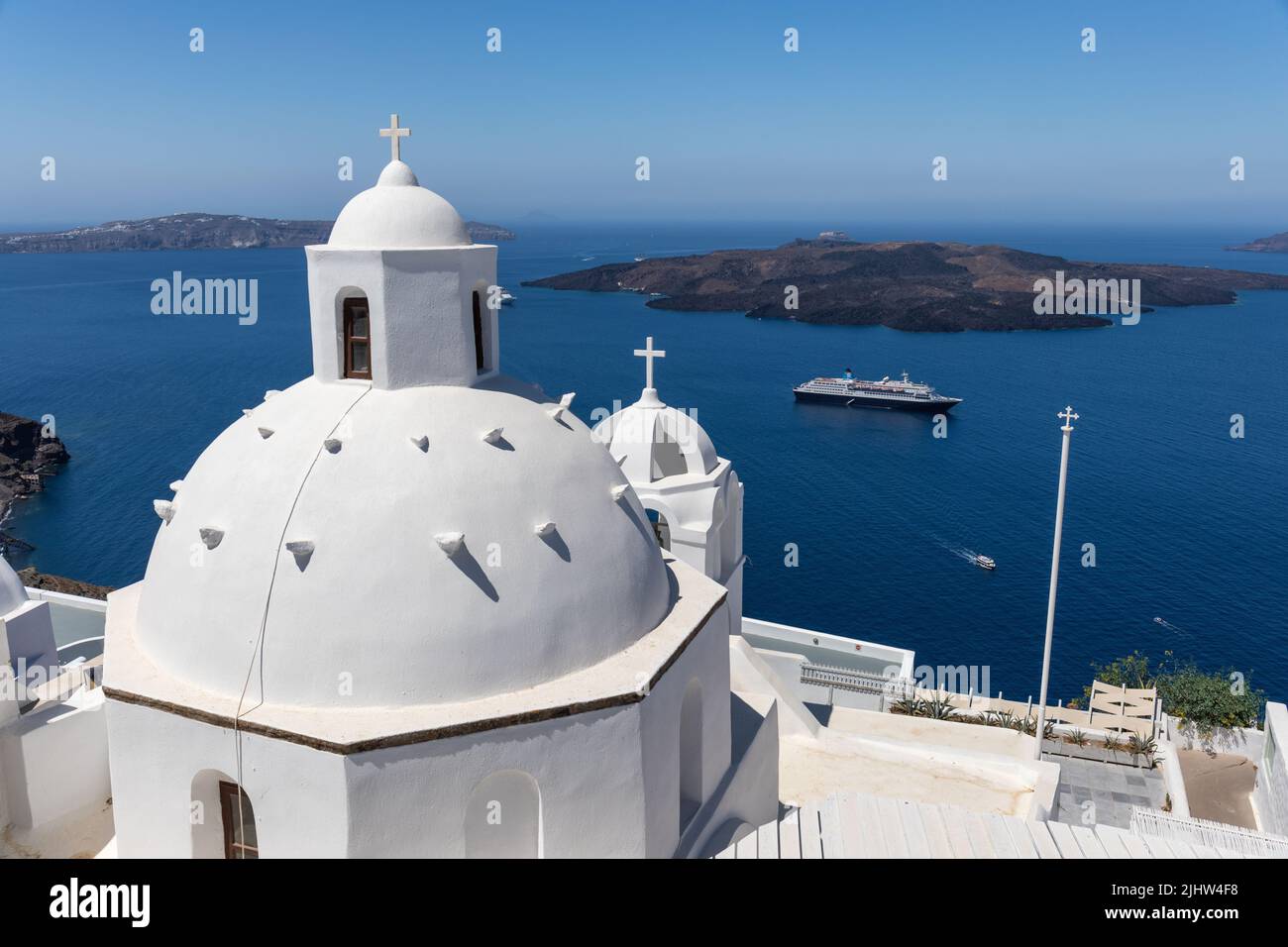 Kirche Agios Minas in Fira / Thira. Eine griechisch-orthodoxe Kirche mit einer weißen Kuppel und einem Glockenturm. Blick auf die Ägäis und den Vulkan, Santorini, Griechenland Stockfoto