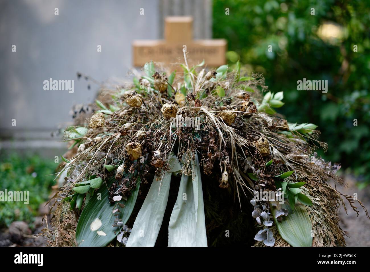 Getrocknete Blumendekoration auf einem traurigen verlassenen Grab Stockfoto