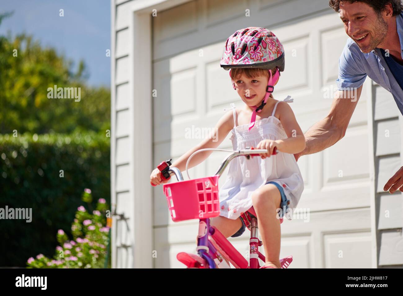 Ein junger Vater lehrt seine Tochter, Fahrrad zu fahren. Stockfoto
