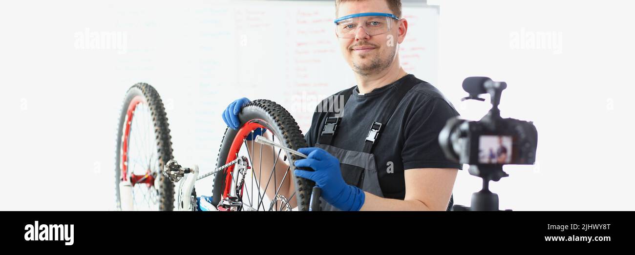Qualifizierter Handwerker, der gebrochenes Fahrrad repariert, Drehprozess auf Videokamera Stockfoto