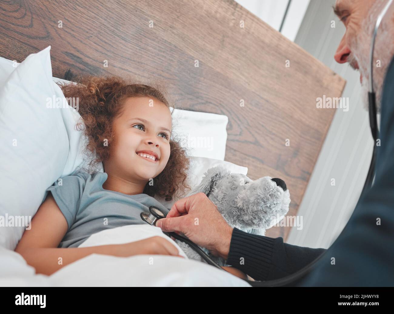 Ein Arzt, der eine Untersuchung an einem kleinen Mädchen zu Hause macht. Stockfoto