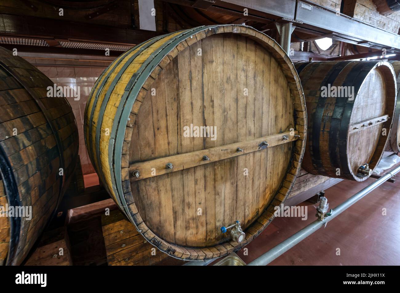 Riesige Holzfässer mit alkoholischen Getränken auf Regalen im Keller Stockfoto