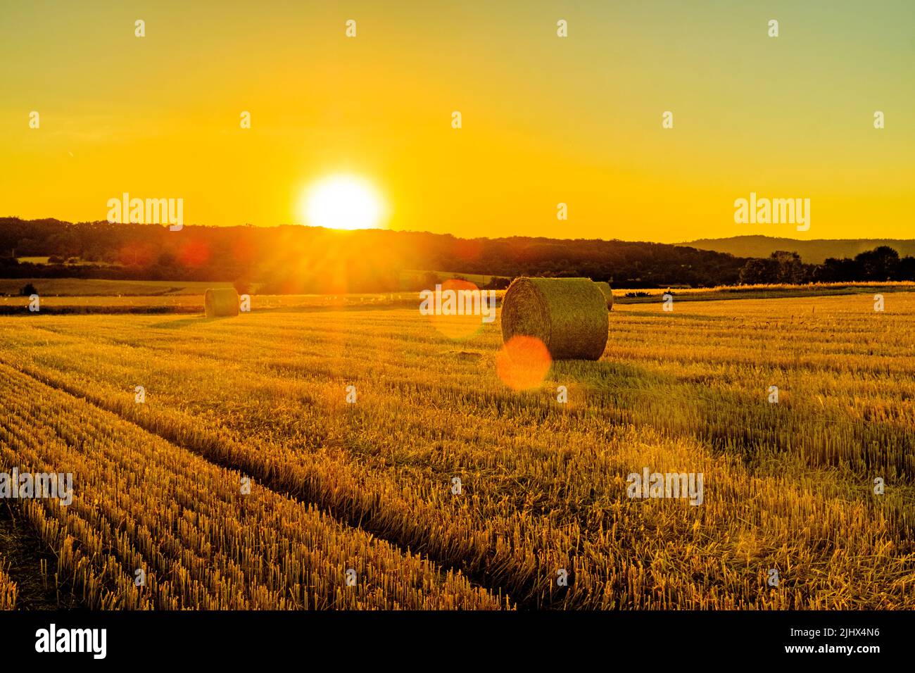 Geerntetes Weizenfeld bei Sonnenuntergang goldene Stunde in Deutschland, Europa. Weizenfeld zur goldenen Stunde mit Sonnenbahn Stockfoto