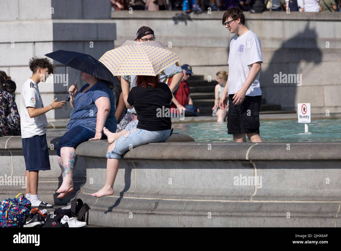 An einem der heißesten Tage in Großbritannien im Sommer, dem 2022. Juli, sitzen sich die Menschen mit ihren Beinen in den Springbrunnen am Trafalgar Square abkühlen. Stockfoto