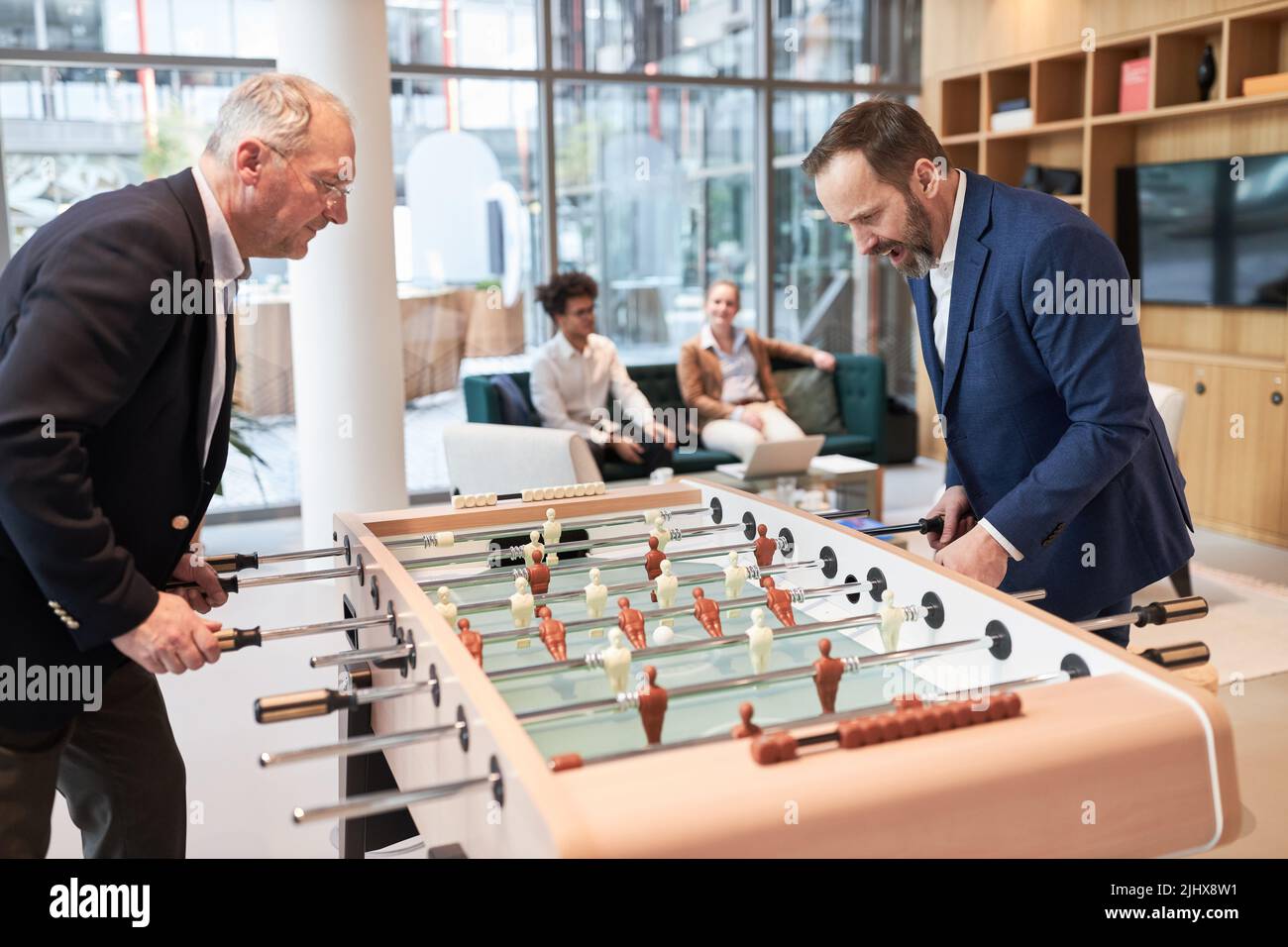 Zwei Geschäftsleute spielen Tischfußball am Tischfußball in der Lounge des Unternehmens Stockfoto