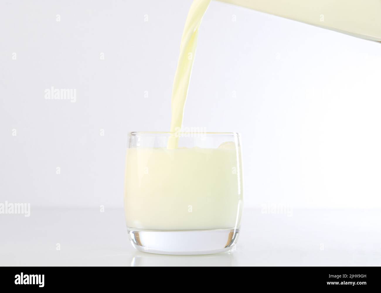 Milch in eine Glasschale gießen Stockfoto