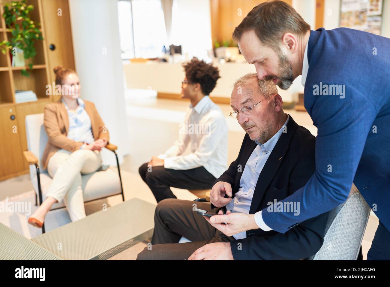 Geschäftsleute lesen in einem Meeting Nachrichten oder sms auf dem Smartphone im Büro Stockfoto