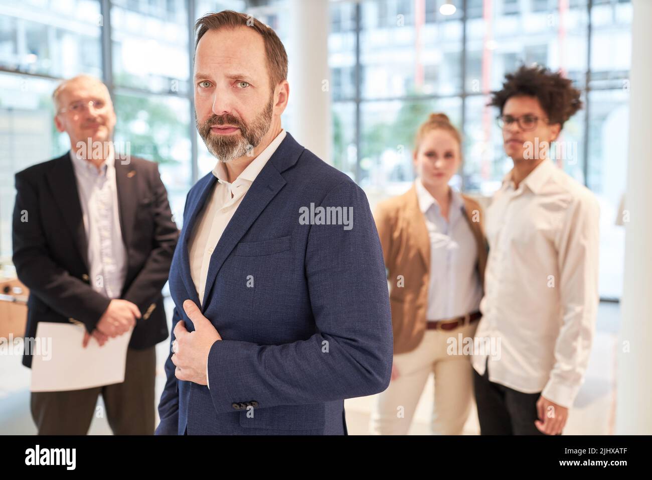 Selbstbewusster Geschäftsmann als Chef und Manager mit seinem Team im Hintergrund Stockfoto
