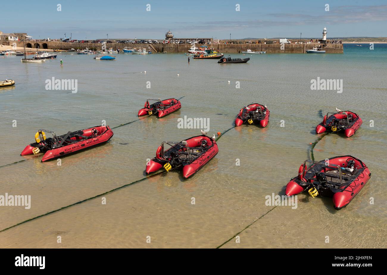 St Ives, Cornwall, England, Großbritannien. 2022. St Ives beliebter Badeort in Cornwall. Fahren Sie selbst rote aufblasbare Boote in flachem Wasser. Stockfoto