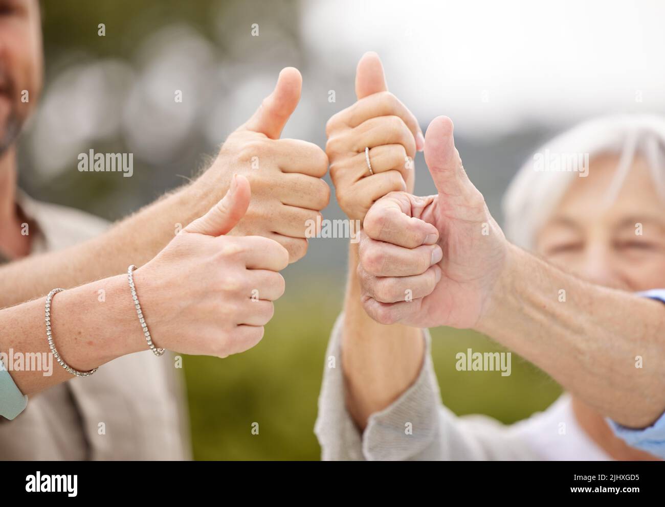 Die Ungezwungenheit des Familienlebens ist ein gesegneter Zustand. Eine nicht erkennbare Familie zeigt Daumen nach oben draußen. Stockfoto