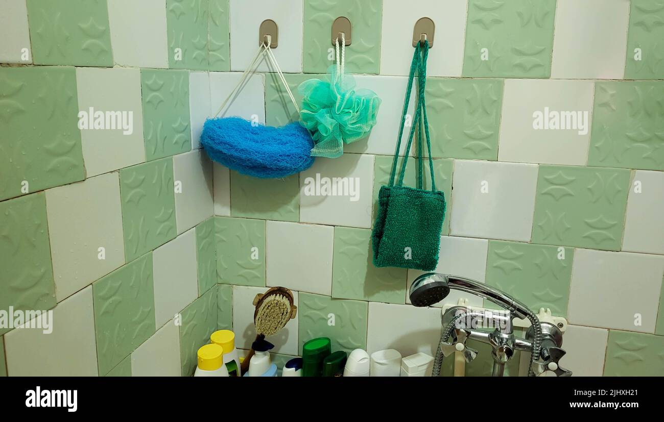 Im Badezimmer hängen synthetische Waschlappen für die Körperpflege an der Wand. Stockfoto