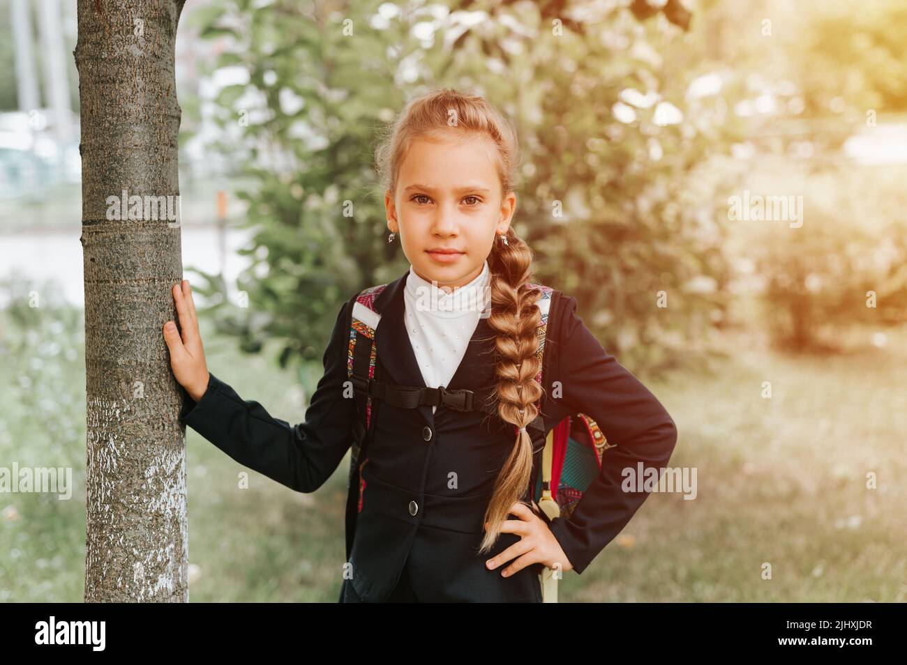 Zurück zur Schule. Kleine glückliche Kind Schüler Schülerin acht Jahre alt in Mode-Uniform mit Rucksack und Frisur voluminösen langen Zopf bereit zu gehen Stockfoto