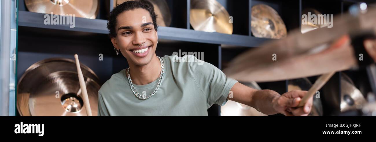 Positiver afroamerikanischer Mann, der im Musikgeschäft Schlagzeug spielt, Banner Stockfoto