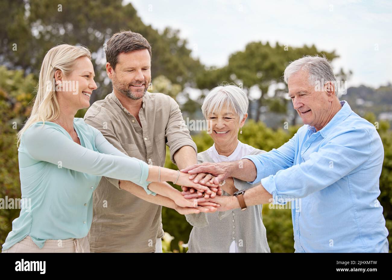 Gehen Sie nach Hause und lieben Sie Ihre Familie. Eine Familie stapelt ihre Hände im Garten draußen. Stockfoto