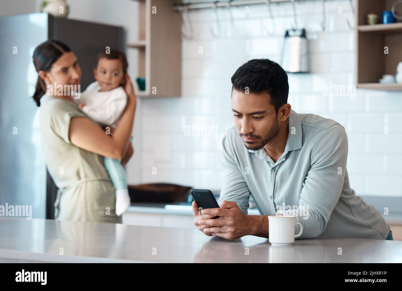 Denken Sie immer daran, was wirklich wichtig ist. Ein junger Mann ignoriert seine Frau und sein Kind, während er sein Telefon zu Hause benutzt. Stockfoto