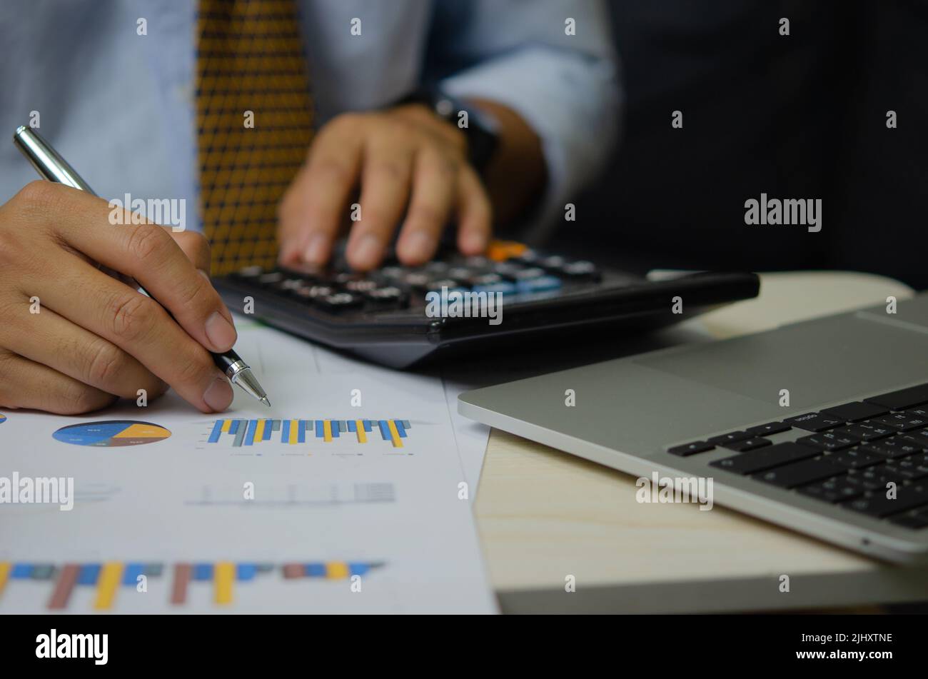 Geschäftsmann Hand Stift mit Grafiken und Diagramme Business-Dokumente Rechner und Computer Laptop.Financial und Steuer-Marketing-Business-Konzept. Stockfoto