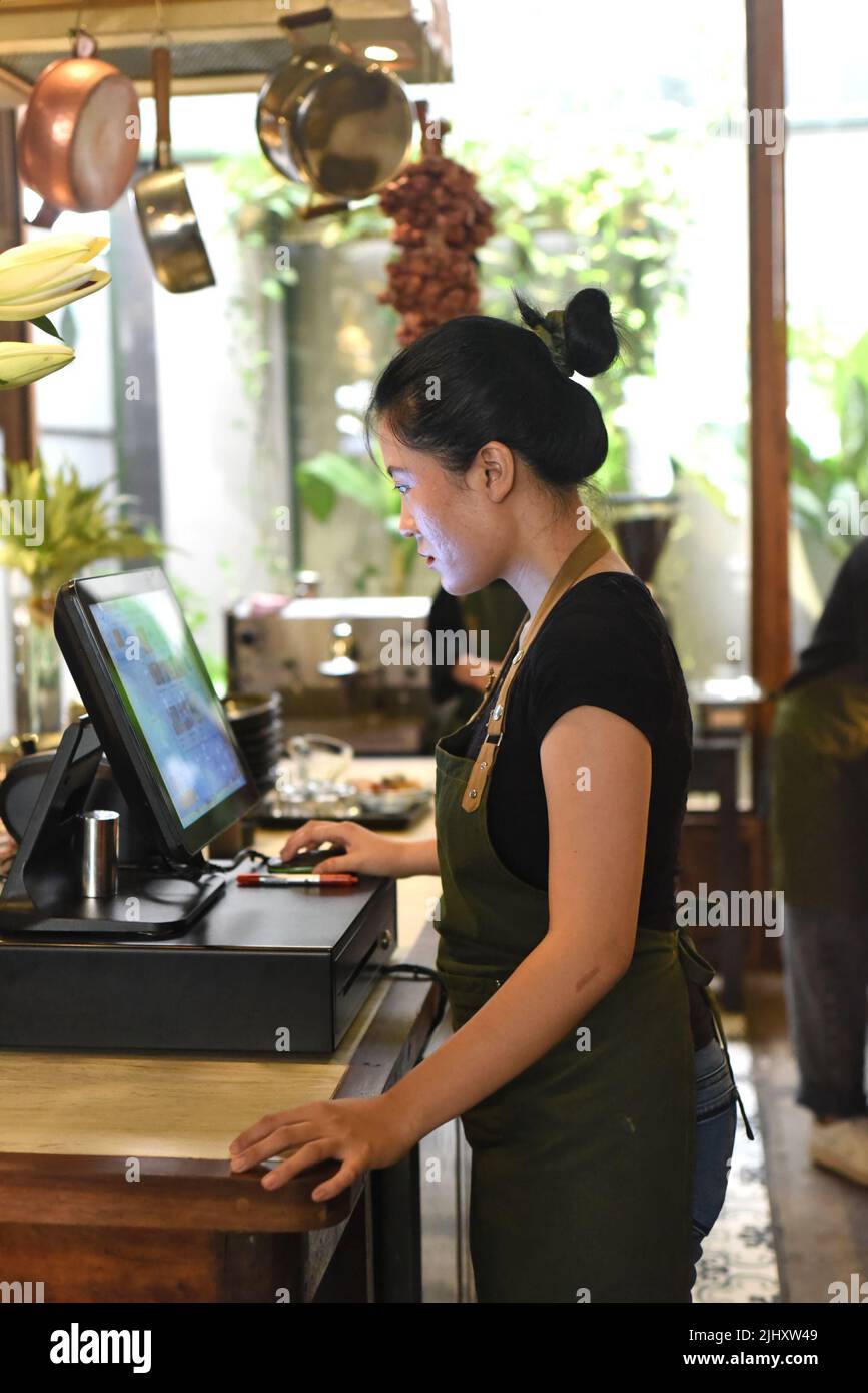 Junge vietnamesische Kellnerin serviert einen Kunden an der Kasse im Café Stockfoto