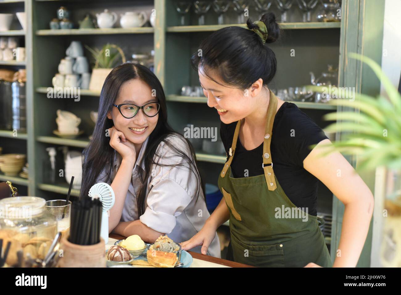 Lächelnde vietnamesische Kellnerin serviert ein Eis mit Waffeln im vietnamesischen Café Stockfoto