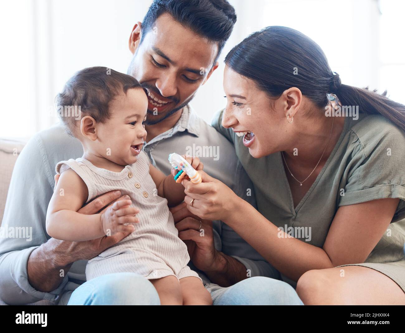 Schnelle kleine Finger. Ein junges Paar, das sich mit ihrem kleinen Mädchen auf einem Sofa zu Hause verklebt. Stockfoto
