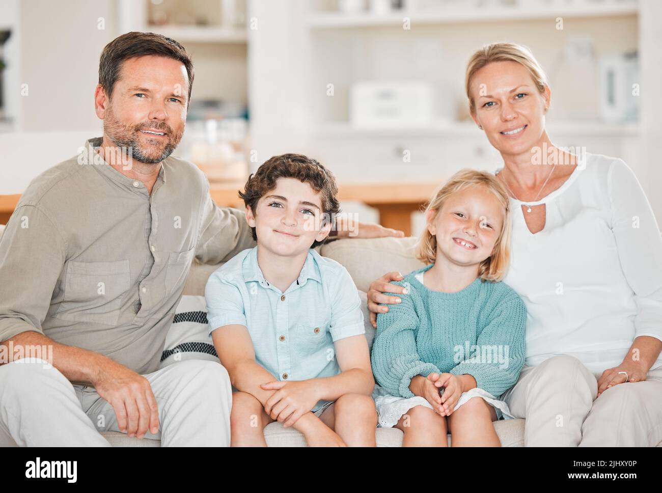 Wir sind Familie. Beschnittenes Porträt einer glücklichen, vierköpfigen Familie, die zu Hause auf dem Sofa sitzt. Stockfoto