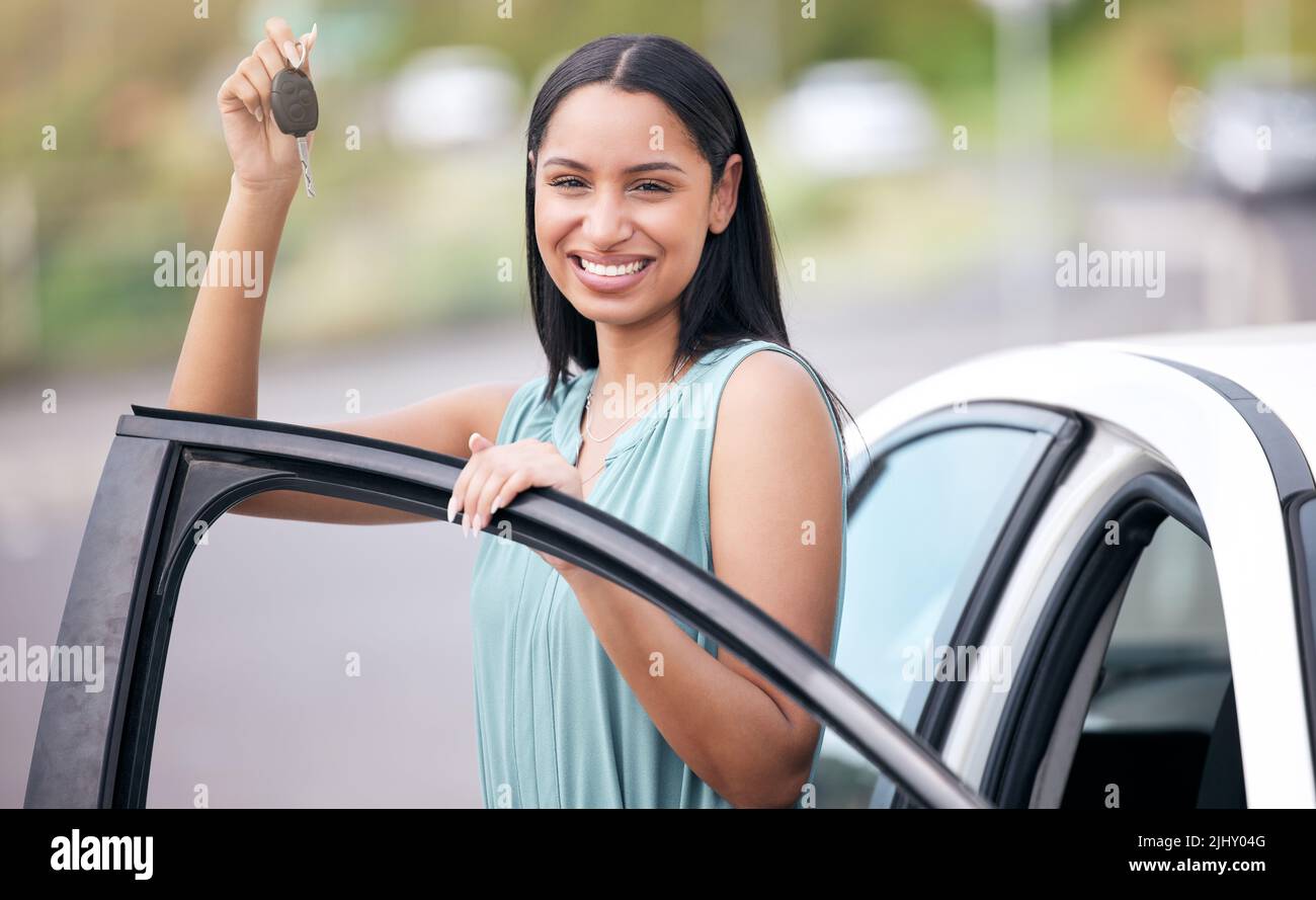 Porträt einer fröhlichen Mixed-Race-Frau mit Schlüsseln für ihr neues Auto. Hispanische Frau schaut glücklich, ihr erstes Auto zu kaufen oder ihren Fahrertest zu bestehen Stockfoto