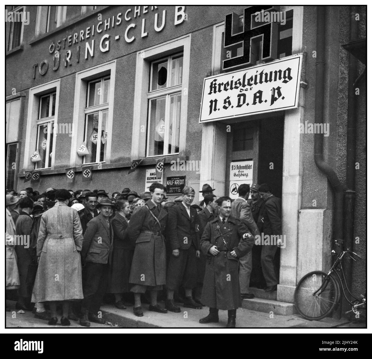 1930s Nazi Salzburg Austria Büro für Arbeitslose mit großem Hakenkreuz über dem Eingang. Erste Hilfssummen werden sofort bezahlt - beste Propaganda für Hitlers 'Sozialismus'. Und Anschluss die Austrian S.A. haben keine Uniformen. Das Brownshirt am Eingang der NSDAP ist ein Deutscher. Alle wichtigen österreichischen Funktionen werden von der deutschen SA, der SS, der Polizei oder der Reichswehr übernommen. Salzburg Österreich Stockfoto