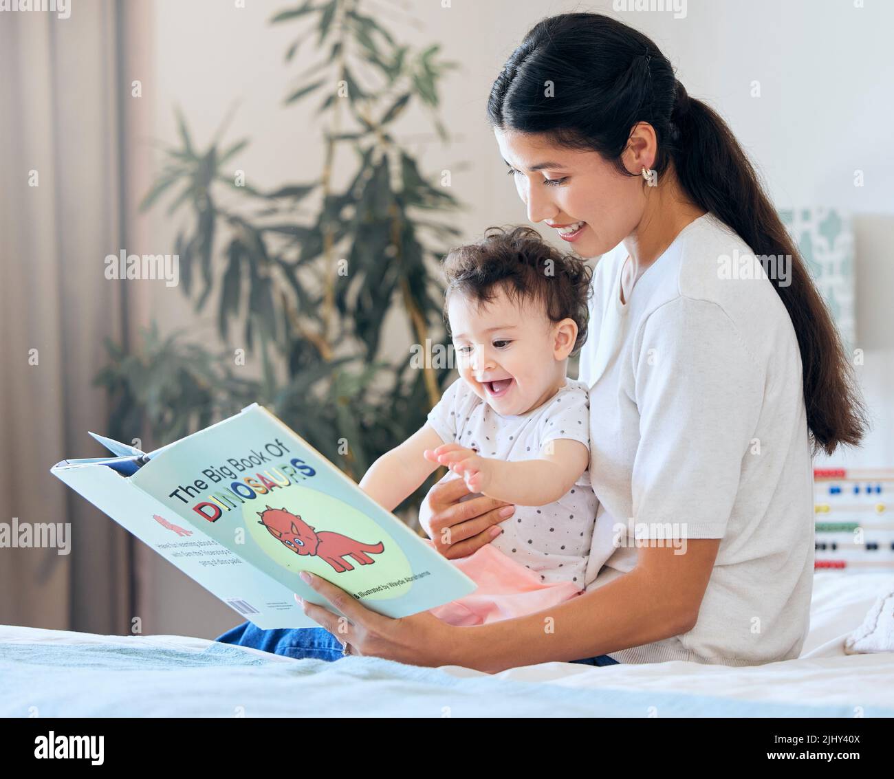 Mutter liest ihrem Baby vor. Elternteil liest ein Storybook. Glückliche Frau, die ihrem Kind vorliest. Mutter hält aufgeregt Baby. Kleines Mädchen, das von einer Geschichte begeistert ist Stockfoto