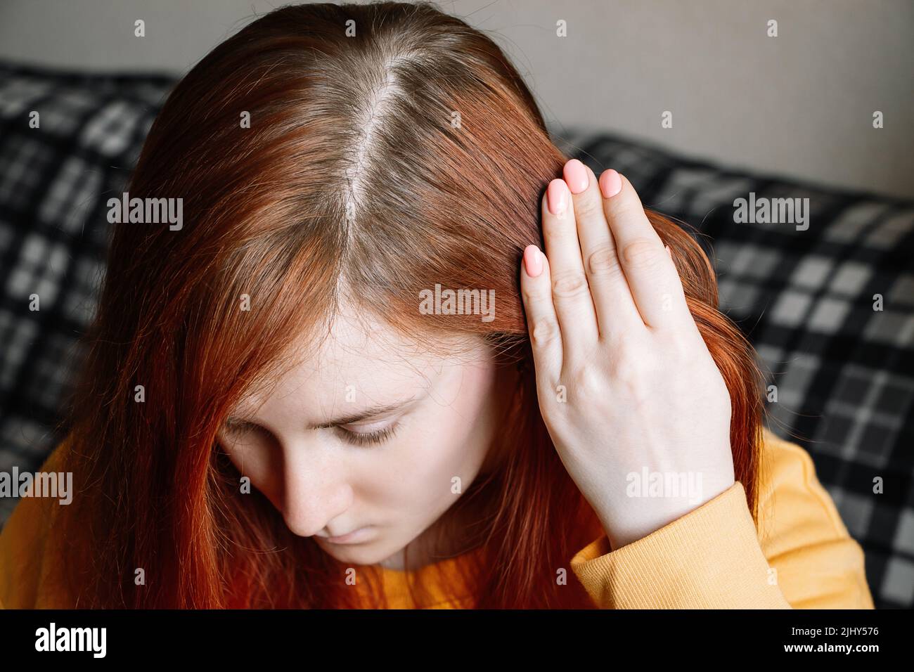 Junge Frau zeigt überwuchert Haarwurzeln. Selbstpflege-Konzept, Haarfärbung zu Hause. Erstes graues Haar. Stockfoto