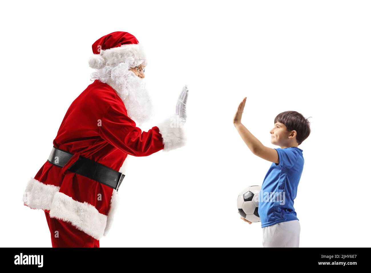 Weihnachtsmann gestikuliert High-five mit einem Jungen in einem Fußballoutfit isoliert auf weißem Hintergrund Stockfoto