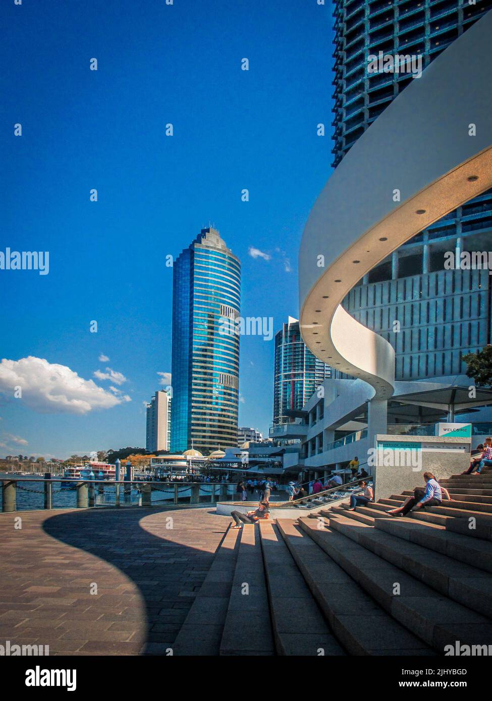 08-14 2014 Brisbane Australien- Menschen, die auf einer Treppe in der Nähe des Flusses sitzen, mit Blick auf die CBD-Wolkenkratzer und die Architektur in Brisbane Stockfoto