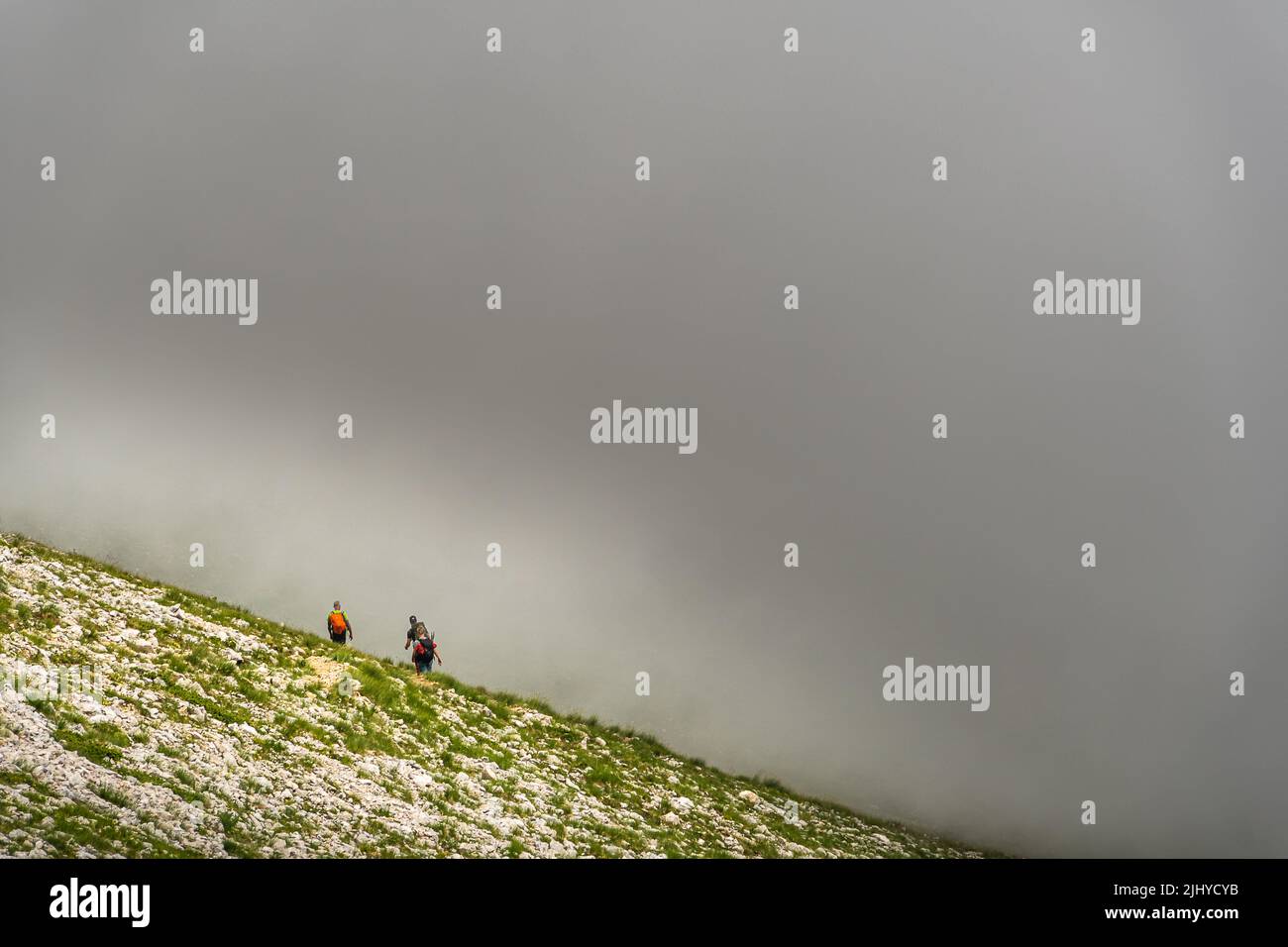 Wanderer betreten die Wolken eines plötzlichen Sturms entlang des Pfades, der vom Monte Camicia absteigt. Gran Sasso und Nationalpark Monti della Laga, Abruzzen Stockfoto