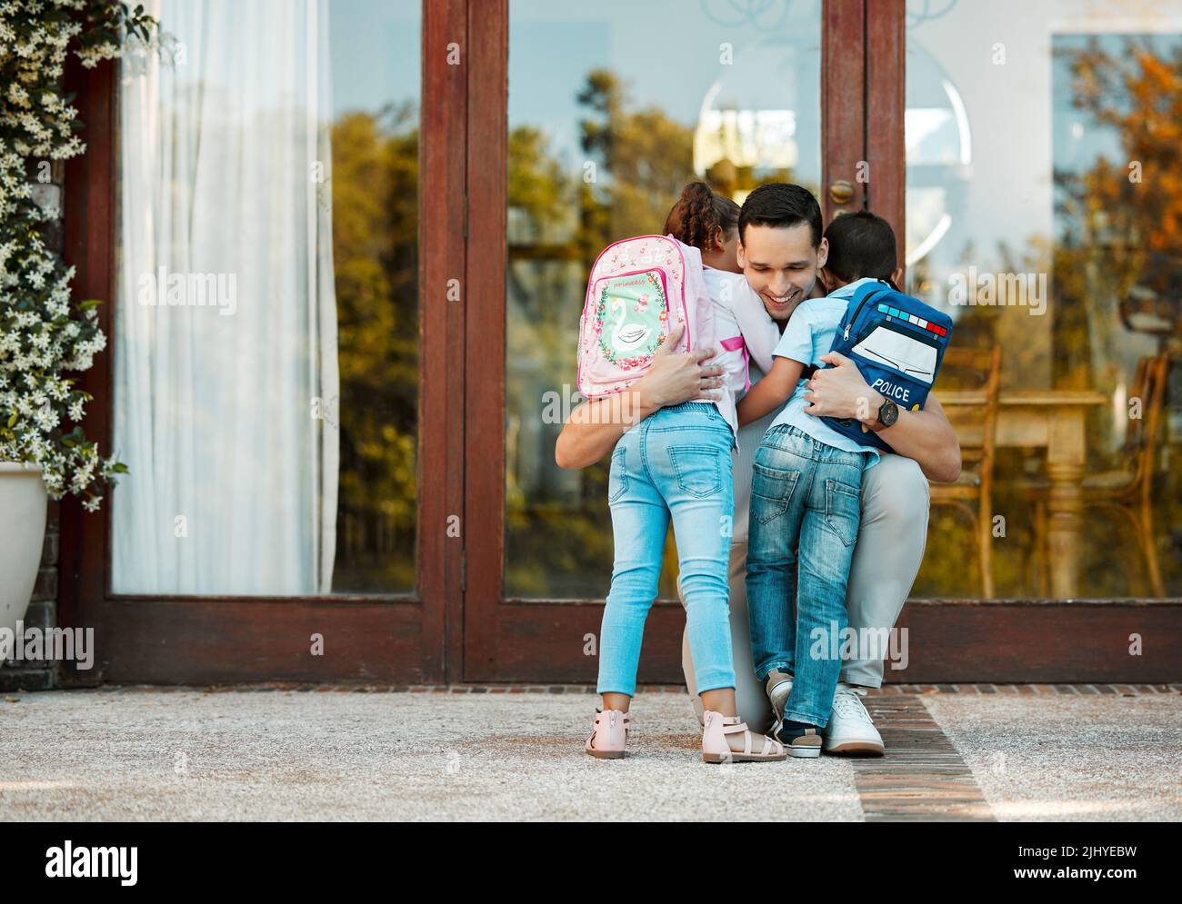 Kinder, die von der Schule zurückkehren und ihren Vater bei ihrer Rückkehr umarmen. Vater vermisste kleine Tochter und Sohn, die Kinder in den Armen hielten und Mädchen und Jungen umarmten Stockfoto