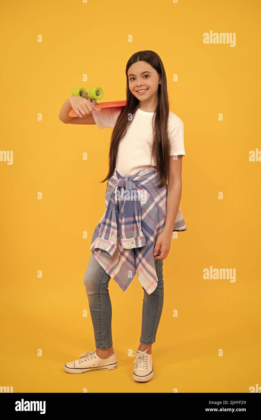 Glücklich Teenager-Mädchen in teen lässig halten pennyboard gelben Hintergrund, Skater Mädchen Stockfoto