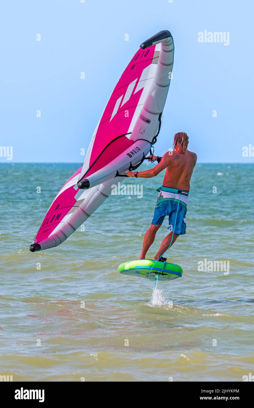 Wing Foiling / Wing Surfing an der Nordsee zeigt Wingboarder / Wing Boarder stehen auf Foilboard / Tragflügelbrett und halten einen aufblasbaren Flügel Stockfoto