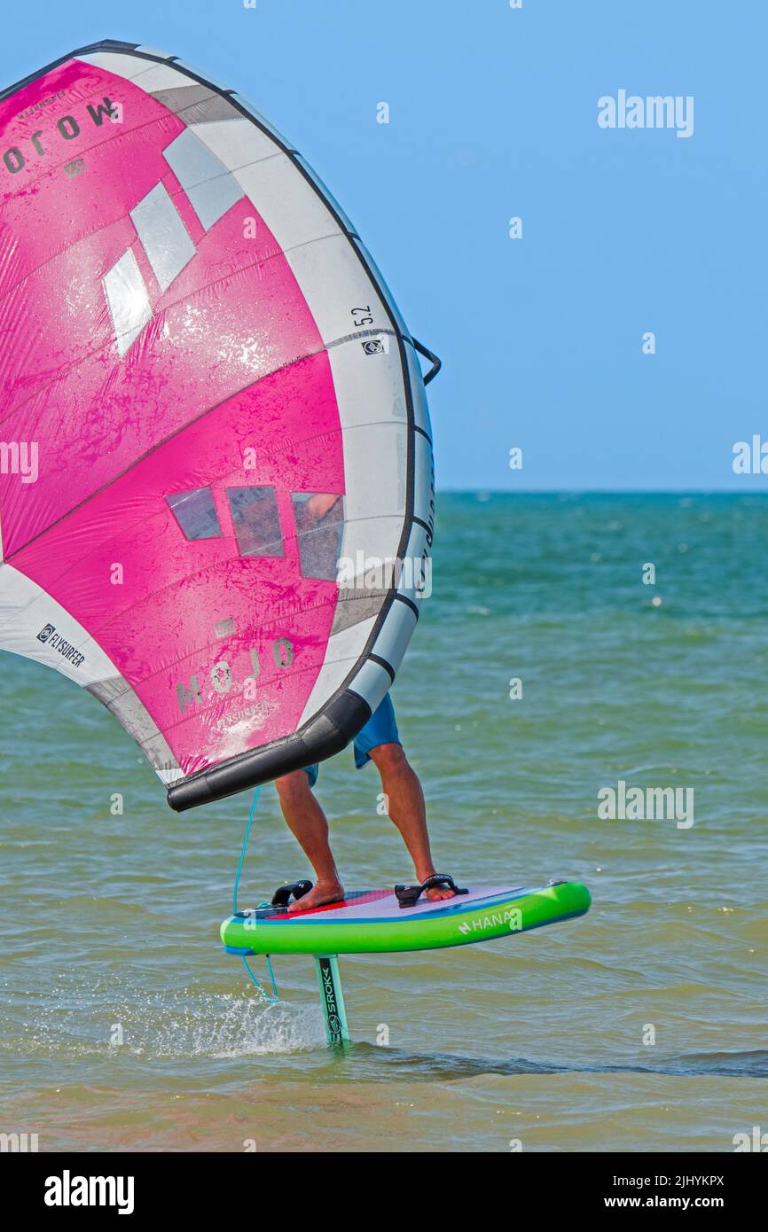 Wing Foiling / Wing Surfing an der Nordsee zeigt Wingboarder / Wing Boarder stehen auf Foilboard / Tragflügelbrett und halten einen aufblasbaren Flügel Stockfoto