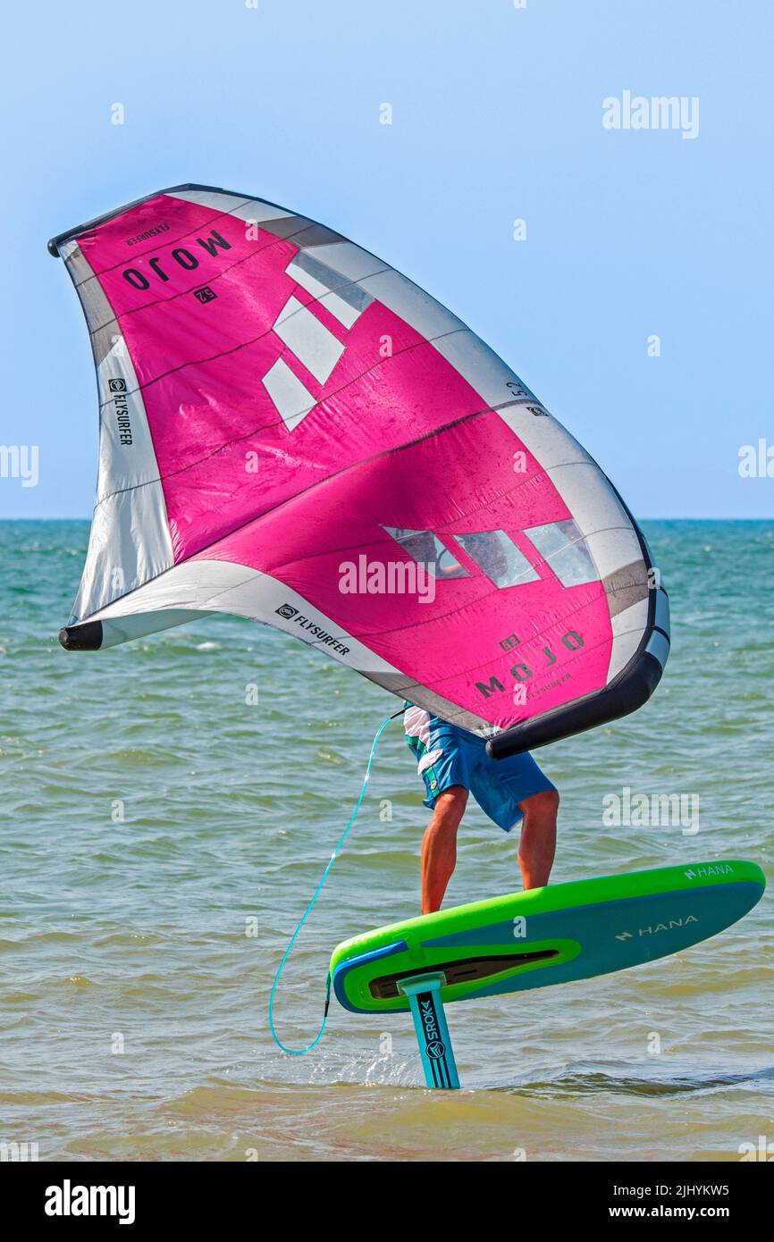 Wing Foiling / Wing Surfing an der Nordsee zeigt Wingboarder / Wing Boarder stehen auf Foilboard / Tragflügelbrett und halten einen aufblasbaren Flügel Stockfoto