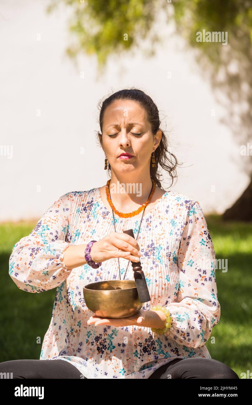 Eine Frau, die während einer Meditations- und Musiktherapie eine tibetische Klangschale spielt. Stockfoto