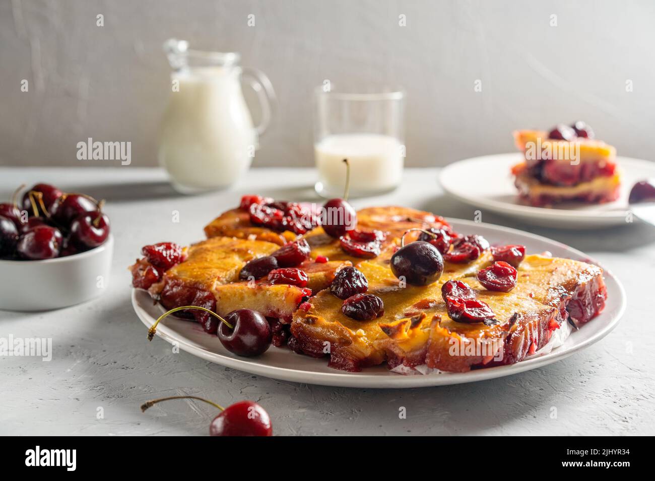 Frisch gebackene süße Kirschkuchen oder roter Brownie-Kuchen auf dem Teller. Rohe Beeren, ein Stück Kuchen und Milch im Bild Stockfoto