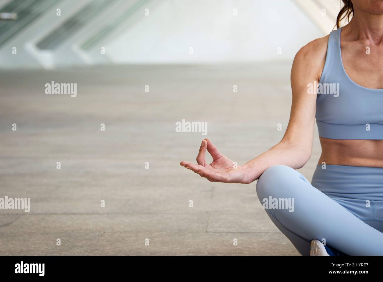 Frau meditiert in einer Yoga-Pose, urbaner konkreter Hintergrund Stockfoto