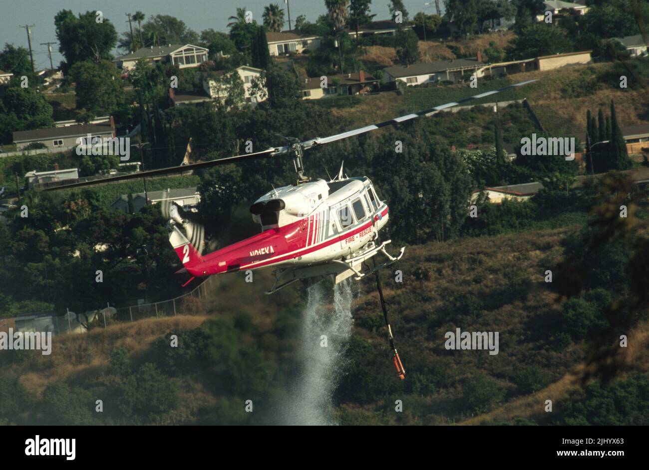 San Diego Regional Fire-Rescue Hubschrauber von Kachina Aviation macht einen Wassertropfen auf einem funktionierenden Wildland (Pinsel) Feuer. Stockfoto