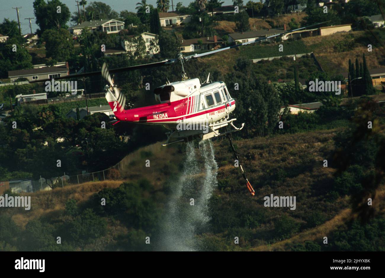 San Diego Regional Fire-Rescue Hubschrauber von Kachina Aviation macht einen Wassertropfen auf einem funktionierenden Wildland (Pinsel) Feuer. Stockfoto