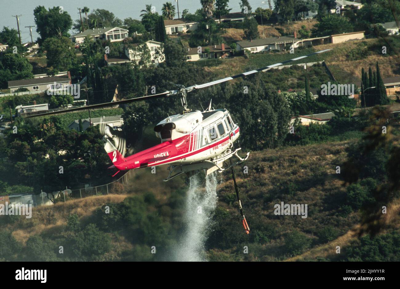 San Diego Regional Fire-Rescue Hubschrauber von Kachina Aviation macht einen Wassertropfen auf einem funktionierenden Wildland (Pinsel) Feuer. Stockfoto